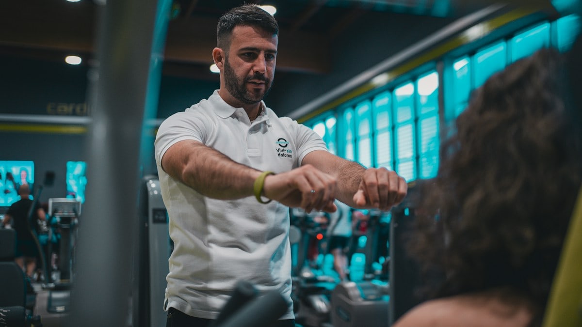 Sesión de entrenamiento en el gimnasio con un entrenador personal, enfocada en el rendimiento y el bienestar físico.